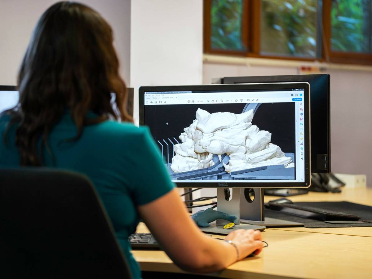 A student seen from behind at a desktop workstation, shaping a 3D model in design software.