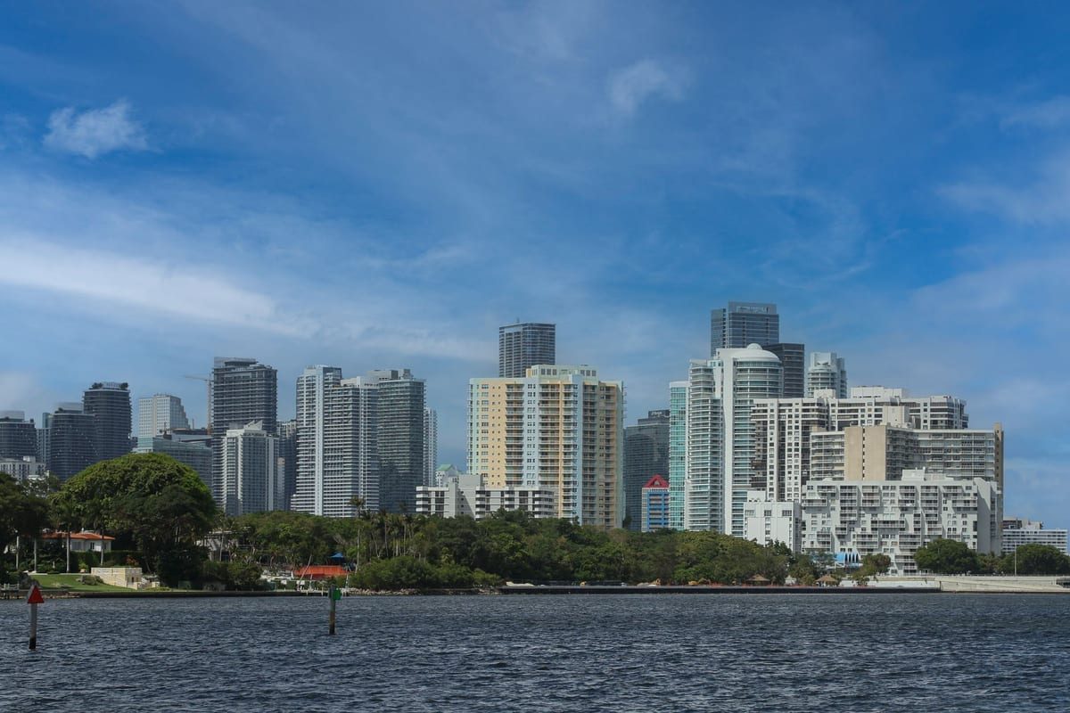 High-rise towers along a waterfront, seen across a bay under a blue sky