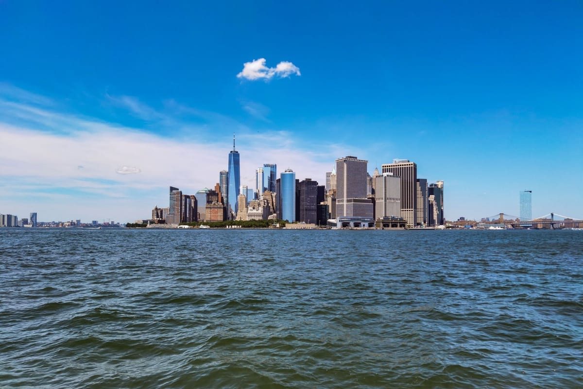 A skyline of towers seen across open, choppy water under a blue sky