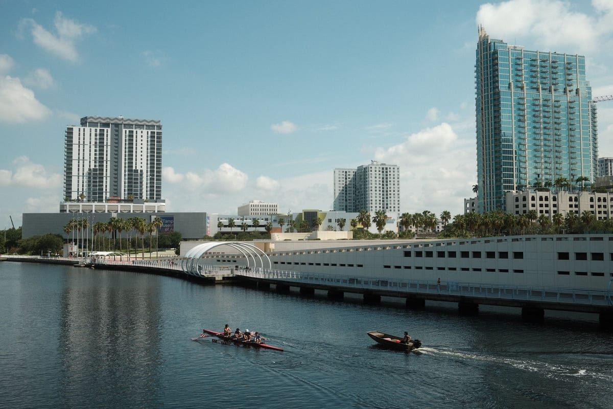 High-rises along a river, with two rowers in a small boat in the foreground