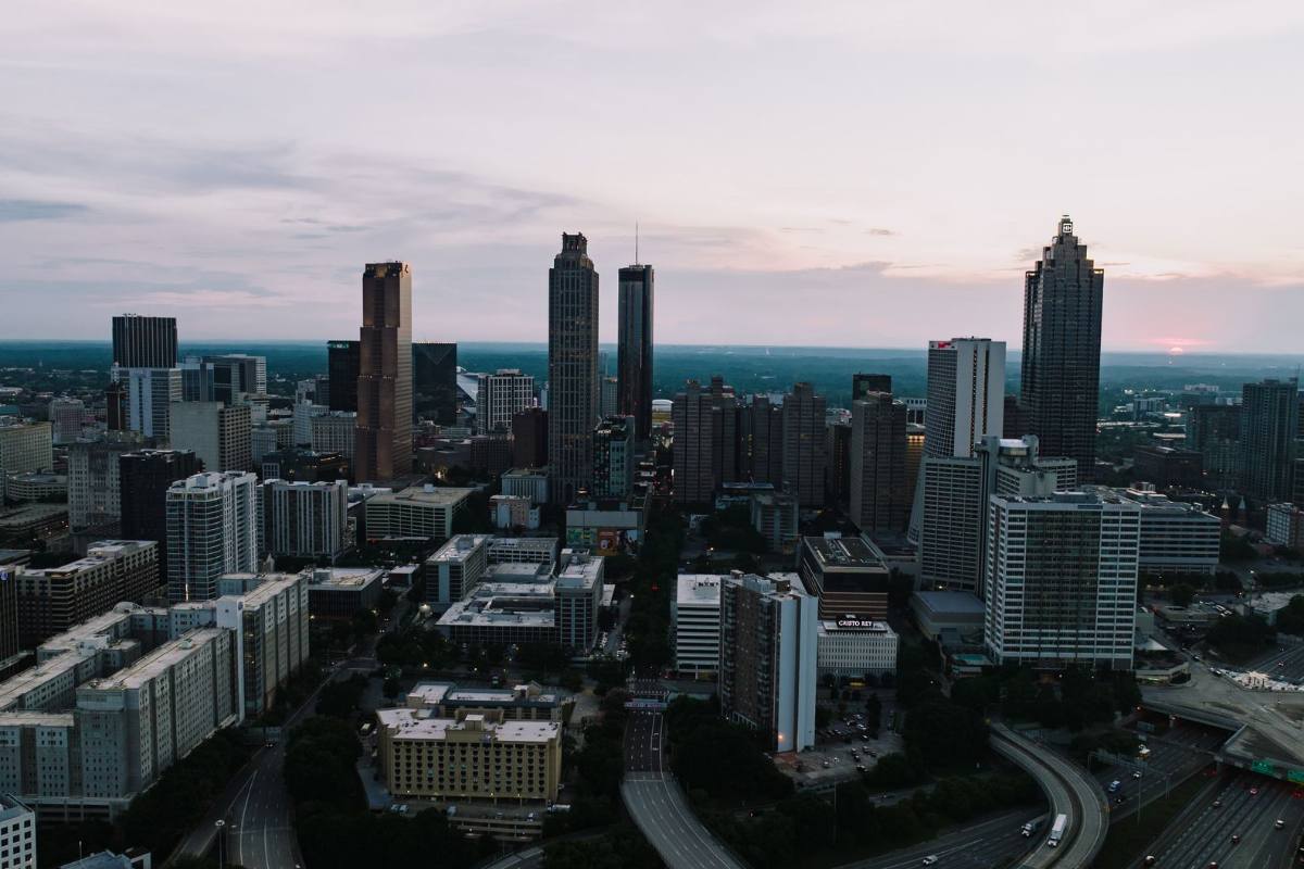 A dense cluster of skyscrapers at dusk above lower city blocks and highways