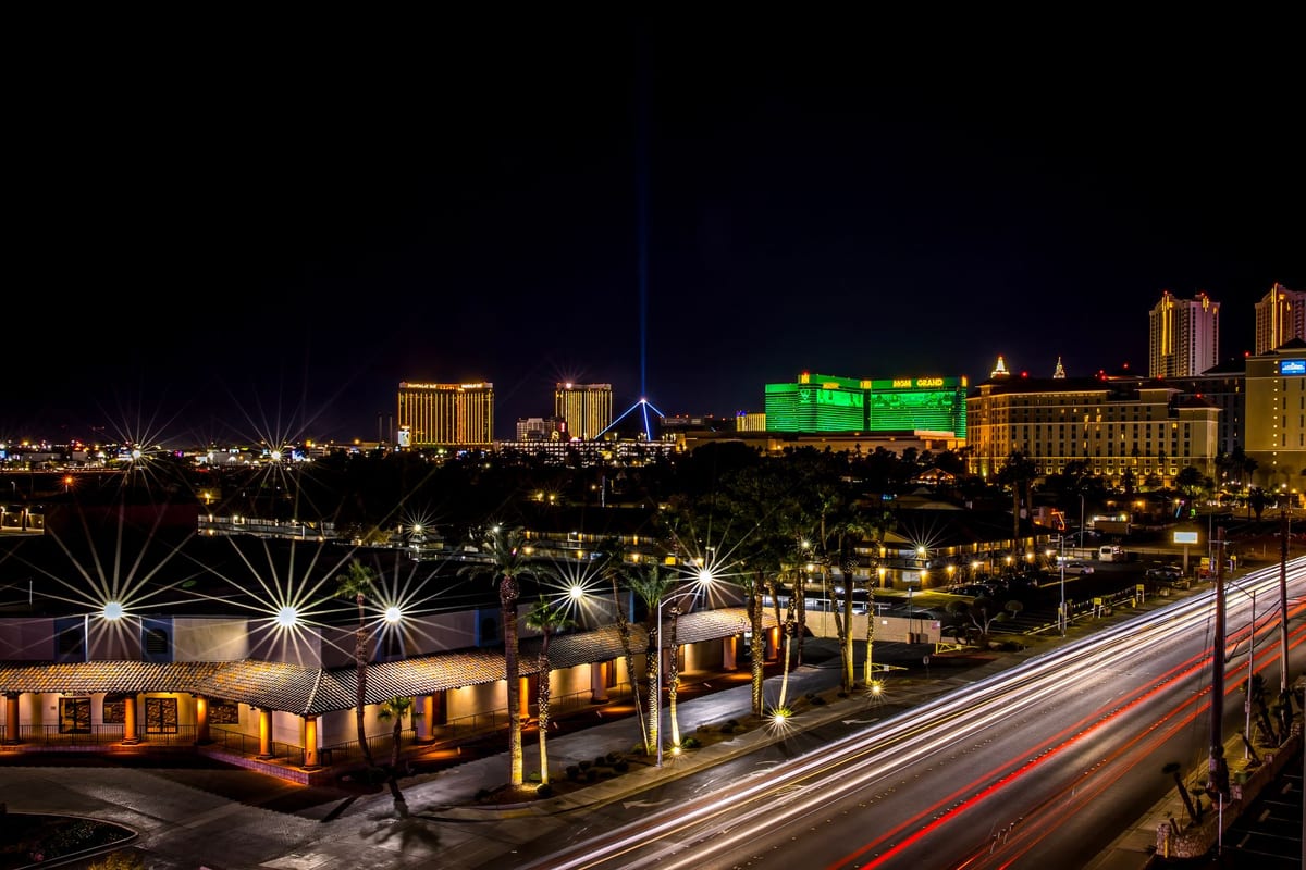Hotel towers lit up at night above a highway streaked with car light trails