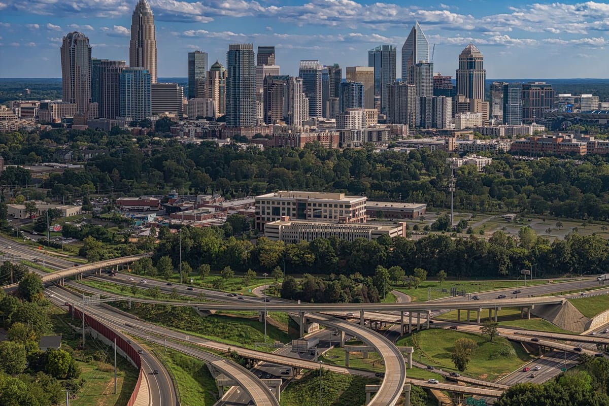 A downtown skyline rising above green trees and a looping highway interchange